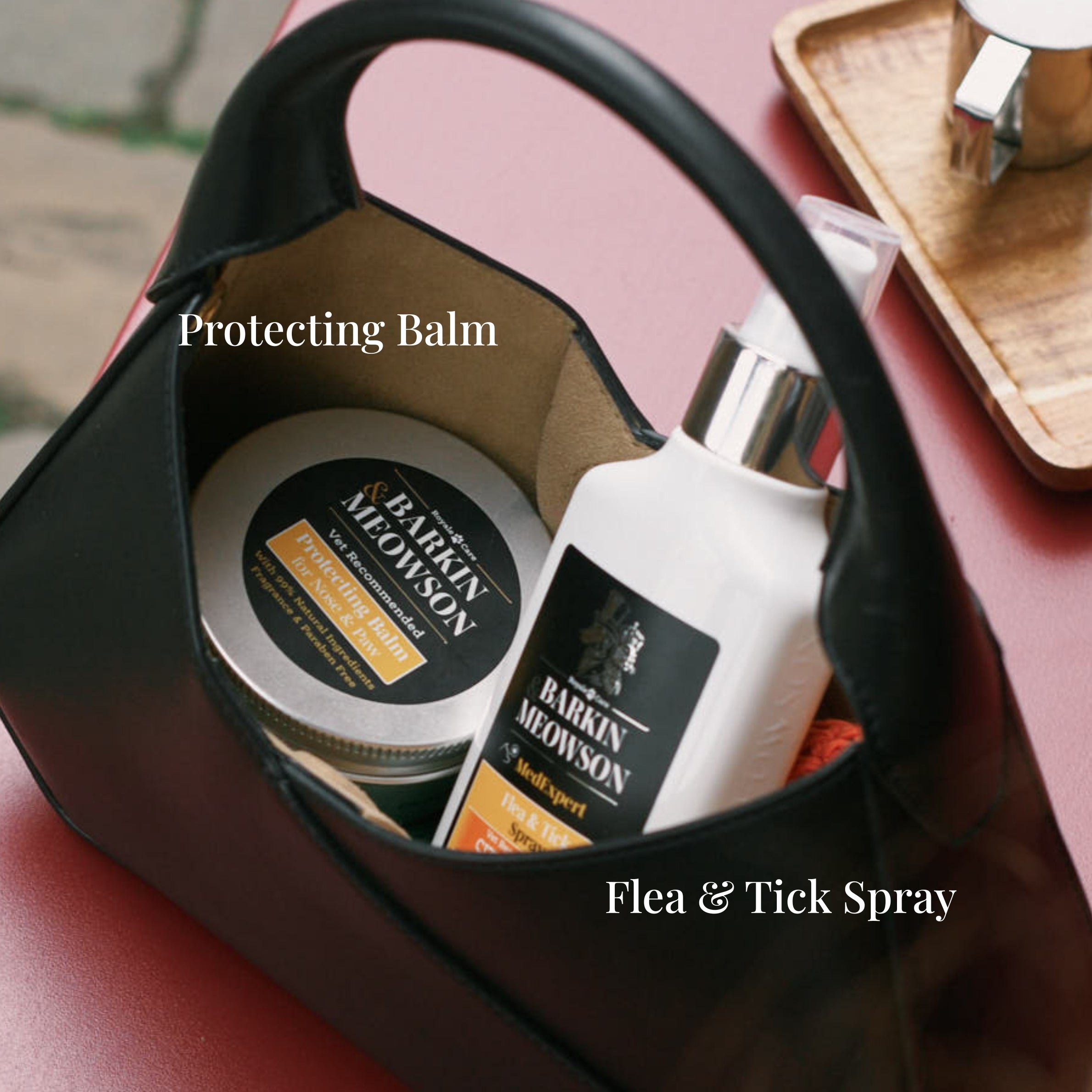 Barking Meowson pet care products including a jar and bottle in a black bag on a pink surface.